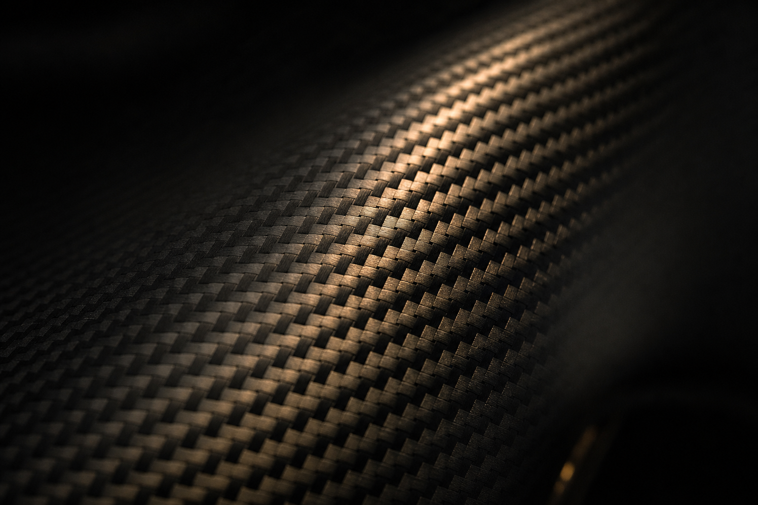 Macro detail of woven carbon-fibre composite under raking amber light